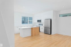 Kitchen featuring appliances with stainless steel finishes, white cabinetry, an island with sink, light wood-style floors, and modern cabinets - 