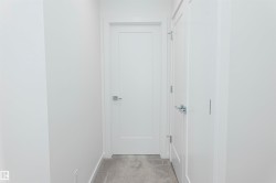 Hallway featuring light colored carpet and baseboards - 
