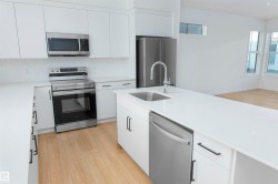 Kitchen with appliances with stainless steel finishes, white cabinets, tasteful backsplash, light wood-style floors, and modern cabinets - 