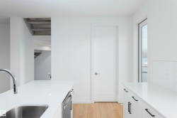 Kitchen featuring light wood-style flooring, white cabinetry, dishwasher, and light stone counters - 