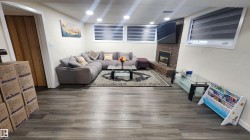 Living area with dark wood-style flooring, a brick fireplace, a textured wall, and recessed lighting - 
