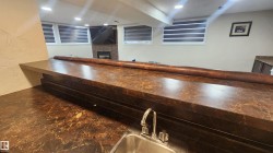 Bar area with a fireplace, a textured wall, wooden counters, and recessed lighting - 