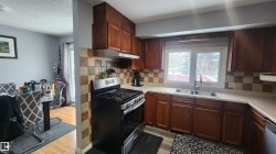 Kitchen featuring appliances with stainless steel finishes, light wood-style floors, light countertops, under cabinet range hood, and a textured ceiling - 