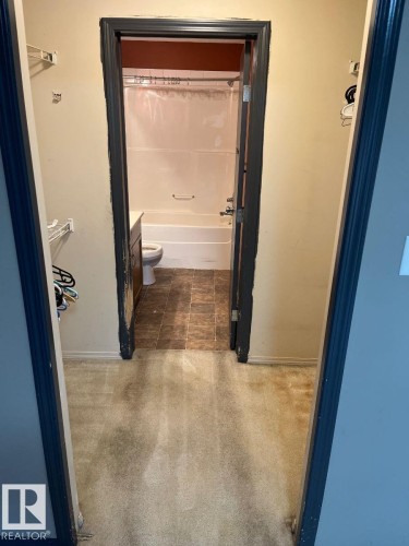 Bathroom featuring vanity, shower / bath combination with curtain, and dark colored carpet - 231 1180 Hyndman Road, Edmonton, AB - Indoor Photo Showing Bathroom