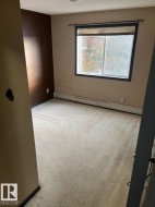 Unfurnished room featuring light carpet, baseboard heating, and a textured ceiling - 