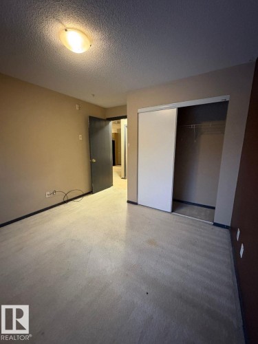 Unfurnished bedroom with a textured ceiling and a closet - 231 1180 Hyndman Road, Edmonton, AB - Indoor Photo Showing Other Room