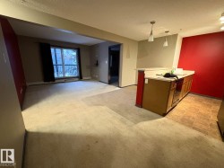 Kitchen with light countertops, light carpet, a peninsula, decorative light fixtures, and open floor plan - 