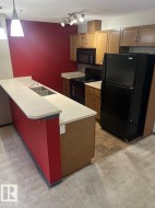 Kitchen featuring black appliances, a breakfast bar, light countertops, a peninsula, and dark carpet - 