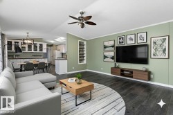 Living room with a chandelier, dark wood-style floors, vaulted ceiling, crown molding, and ceiling fan - 