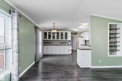 Kitchen with white cabinetry, hanging light fixtures, dark countertops, ornamental molding, and a chandelier - 