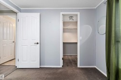 Unfurnished bedroom featuring crown molding, a walk in closet, dark carpet, and a textured ceiling - 