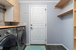 Laundry room featuring dark wood finished floors, crown molding, washer and dryer, and a textured ceiling - 