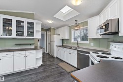 Kitchen featuring open shelves, white cabinets, glass insert cabinets, appliances with stainless steel finishes, and ornamental molding - 