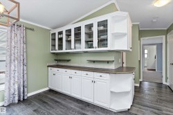 Kitchen featuring ornamental molding, white cabinets, dark wood-style floors, glass insert cabinets, and dark countertops - 