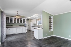 Kitchen with decorative light fixtures, white cabinets, crown molding, dark countertops, and a skylight - 