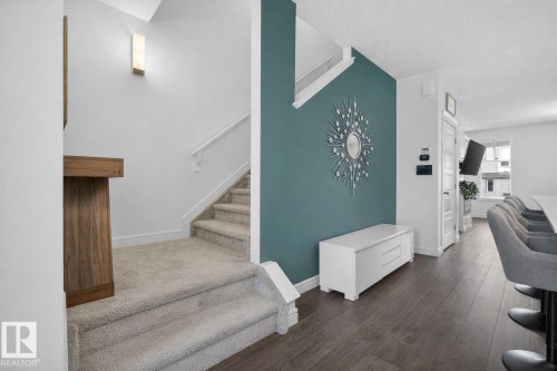 The property features a staircase with carpeted treads and a white handrail, complementing the white walls and a distinctive accent wall - 8 Daniel Street, Fort Saskatchewan, AB - Indoor