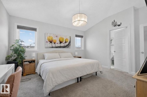 This bedroom features soft grey carpeting, a vaulted ceiling, and two windows providing natural light - 8 Daniel Street, Fort Saskatchewan, AB - Indoor Photo Showing Bedroom