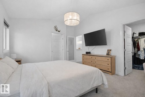 This bedroom features a vaulted ceiling, a window with a roller blind, and a neutral color palette - 8 Daniel Street, Fort Saskatchewan, AB - Indoor Photo Showing Bedroom