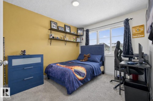 This room features soft gray carpeting, a large window, and shelving along one wall - 8 Daniel Street, Fort Saskatchewan, AB - Indoor Photo Showing Bedroom