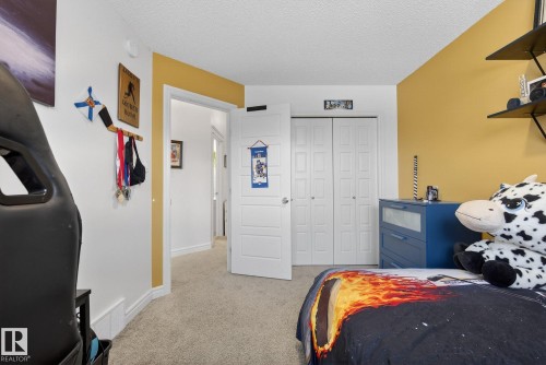 This room features light-colored carpet flooring, white baseboards, and a combination of white and yellow painted walls - 8 Daniel Street, Fort Saskatchewan, AB - Indoor Photo Showing Bedroom