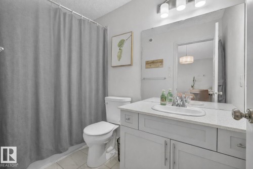 The bathroom features a white vanity with a light-colored countertop and an integrated sink, illuminated by a three-light fixture - 8 Daniel Street, Fort Saskatchewan, AB - Indoor Photo Showing Bathroom
