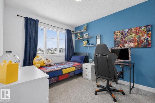 This room features a window with exterior views, light grey carpeting, and a vibrant blue accent wall - 8 Daniel Street, Fort Saskatchewan, AB - Indoor Photo Showing Bedroom