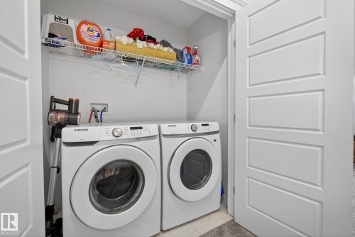 Dedicated laundry area featuring a washer and dryer, with a wall-mounted shelf providing additional storage - 8 Daniel Street, Fort Saskatchewan, AB - Indoor Photo Showing Laundry Room