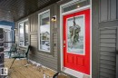 Inviting front porch featuring a vibrant red door, a transom window, and a wood deck - 8 Daniel Street, Fort Saskatchewan, AB  - Outdoor With Deck Patio Veranda With Exterior 