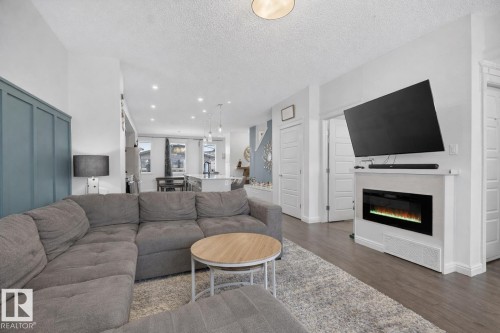 Living room featuring light-colored flooring, a modern electric fireplace, and a decorative accent wall - 8 Daniel Street, Fort Saskatchewan, AB - Indoor Photo Showing Living Room With Fireplace