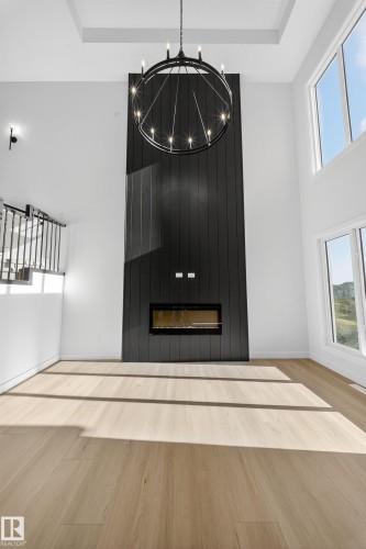 Detailed view of wood finished floors and a chandelier - 3285 Chernowski Way Sw, Edmonton, AB - Indoor Photo Showing Other Room