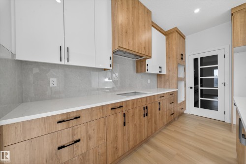 Kitchen featuring light wood-type flooring, light stone countertops, recessed lighting, tasteful backsplash, and white cabinets - 3285 Chernowski Way Sw, Edmonton, AB - Indoor Photo Showing Kitchen