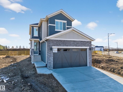 View of front of home featuring a garage, stone siding, and driveway - 3285 Chernowski Way Sw, Edmonton, AB - Outdoor