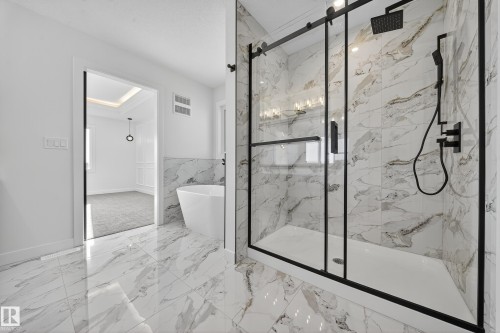 Full bath with a freestanding tub, a marble finish shower, wainscoting, light marble finish flooring, and tile walls - 3285 Chernowski Way Sw, Edmonton, AB - Indoor Photo Showing Other Room