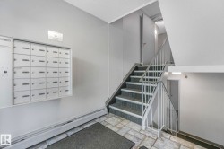 Stairway featuring baseboard heating, stone tile flooring, and mail area - 