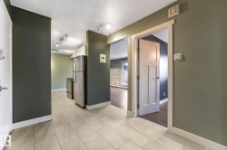 Hallway with a textured ceiling, light tile patterned floors, and baseboard heating - 
