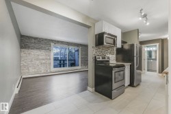 Kitchen featuring stainless steel appliances, white cabinets, light tile patterned floors, baseboard heating, and decorative backsplash - 