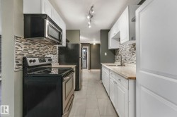 Kitchen featuring appliances with stainless steel finishes, light countertops, white cabinets, and light tile patterned floors - 
