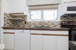 Kitchen featuring white cabinetry, white appliances, and plenty of natural light - 