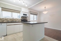 Kitchen featuring white cabinets, light wood-style floors, tasteful backsplash, and white appliances - 