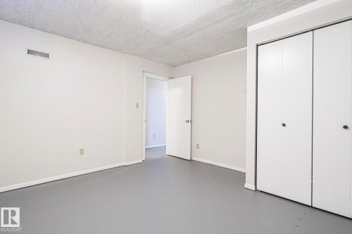 Unfurnished bedroom featuring concrete flooring, a textured ceiling, and a closet - 13419 102 Street, Edmonton, AB - Indoor Photo Showing Other Room
