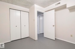 Unfurnished bedroom featuring a textured ceiling, finished concrete flooring, and a closet - 