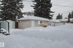 View of snowy exterior with stucco siding and a shed - 
