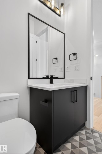The bathroom features a modern vanity with a white countertop, a black framed mirror, and a geometric pattern tile floor - 27 Rosewood Way, St. Albert, AB - Indoor Photo Showing Bathroom