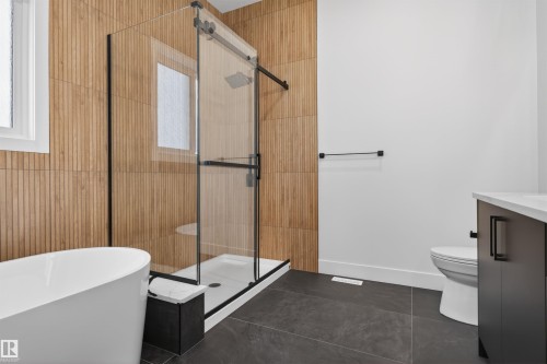 This bathroom features a freestanding bathtub, a glass-enclosed shower with a rainfall showerhead, and a vanity with a white countertop - 27 Rosewood Way, St. Albert, AB - Indoor Photo Showing Bathroom