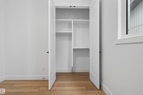 This space features light hardwood floors, white walls, and a window with white trim - 27 Rosewood Way, St. Albert, AB - Indoor Photo Showing Other Room