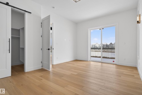 This room features hardwood flooring, white walls, and a large sliding glass door opening to a railing - 27 Rosewood Way, St. Albert, AB - Indoor Photo Showing Other Room