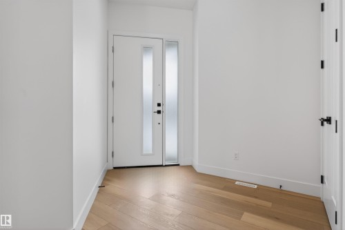Inviting entryway featuring light-toned hardwood floors and a white door with frosted glass panels - 27 Rosewood Way, St. Albert, AB - Indoor Photo Showing Other Room
