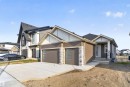Modern exterior featuring a prominent two-car garage with frosted glass panels, stone accents, and brown horizontal siding - 27 Rosewood Way, St. Albert, AB  - Outdoor With Facade 