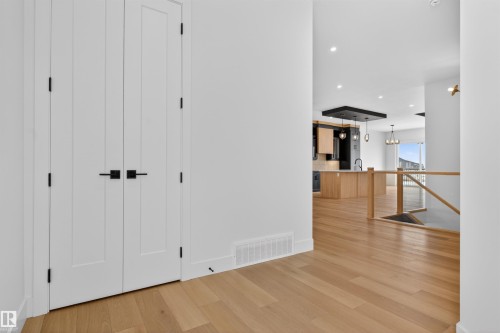 The property features light-toned hardwood flooring throughout, white walls, and white double doors with matte black hardware - 27 Rosewood Way, St. Albert, AB - Indoor Photo Showing Other Room