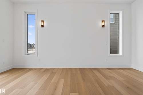 This room features light hardwood flooring, white walls, and two tall vertical windows with white trim - 27 Rosewood Way, St. Albert, AB - Indoor Photo Showing Other Room